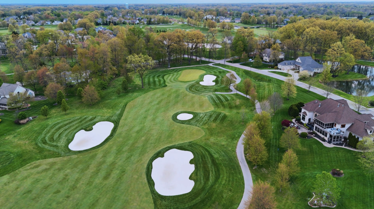 Aerial view of a golf course with fairways, bunkers and surrounding trees